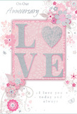 In this image, an anniversary card offers a softly spoken celebration of enduring romance, its palette blending pastel pinks, silvery greys, and gentle whites reminiscent of a tranquil Herne Hill morning. The centre of the design features the word LOVE in softly raised glitter lettering, each stroke subtle yet distinct. The O is replaced by a shimmering silver heart, slightly more textured and lustrous than the rest of the word, creating a natural focal point, like the star bloom in a bouquet. Surrounding this central motif, delicate blossoms in blush and mauve unfold with a watercolour softness, their edges defined by fine, sweeping lines. These lines suggest careful artistry and a sense of movement, calling to mind flowers gently arranged by hand in a local Herne Hill studio for an intimate anniversary celebration. Tiny decorative elements-curled swirls, scattered petals, and almost-hidden butterflies-float among the flowers, adding whimsy and a feeling of light motion, as though a gentle breeze were passing over an English spring garden. The background is a soothing blush pink, even and velvety, allowing the silvers and soft petals to glow. At the top or bottom of the design, the phrase On Our Anniversary appears in an understated script, balanced by the loving message I love you today and always in similarly graceful lettering. The overall composition exudes quiet intimacy, like a heartfelt whisper shared over coffee in a favourite Herne Hill café, and makes the card feel like a treasured keepsake of a shared journey, tender yet profoundly meaningful.
